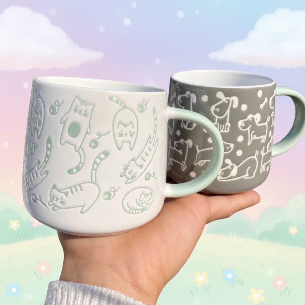 Two mugs with animal patterns held by a hand outdoors.