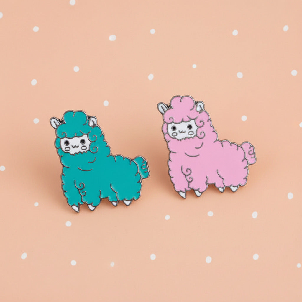 Pair of blue and pink alpaca-shaped earrings on a white dish with a peach colored background.