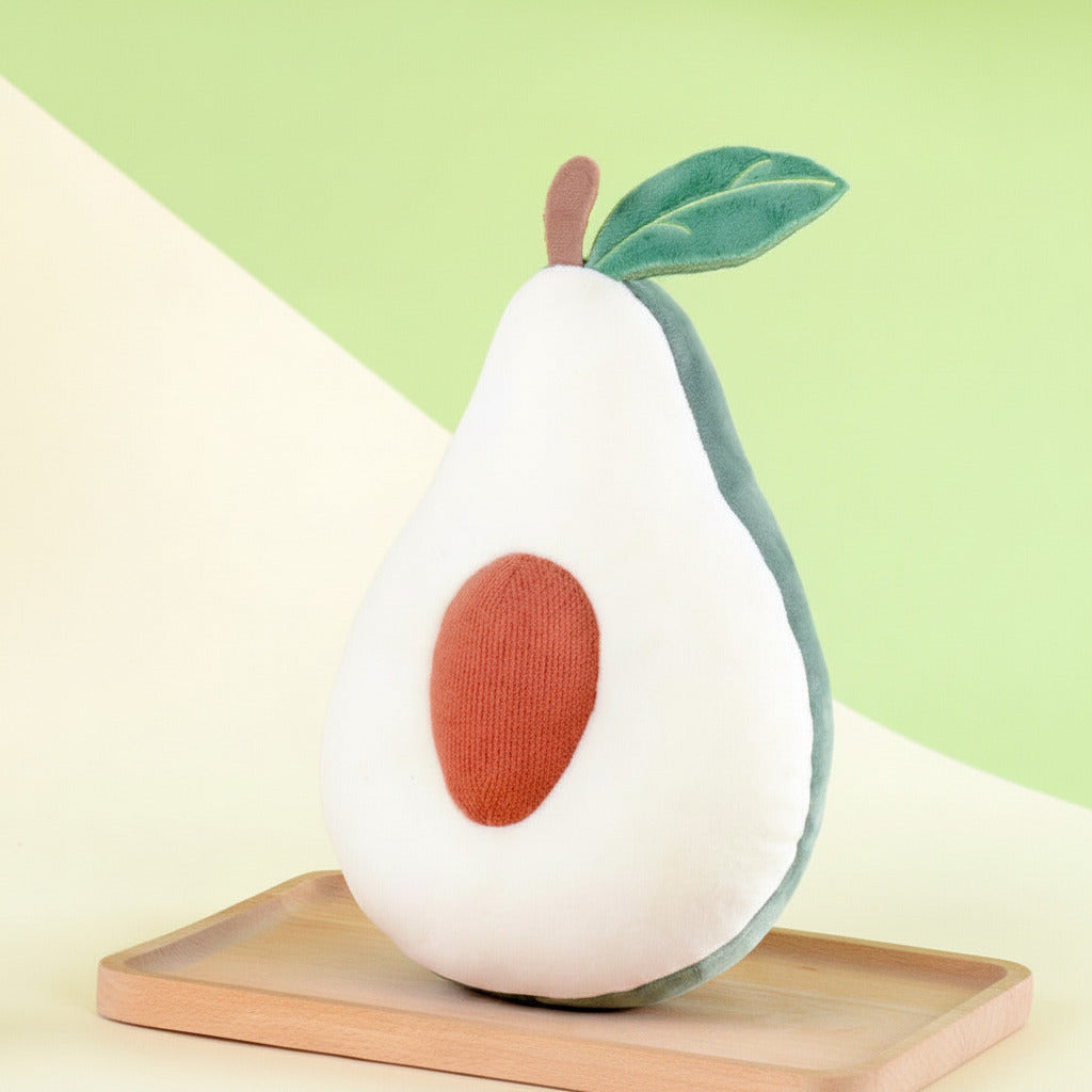 Avocado-shaped plush toy with a sliced avocado on a wooden board against a green background