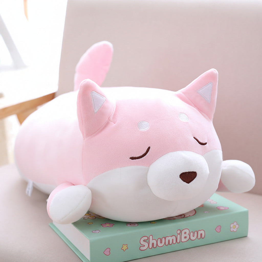 Pink and white plush toy resembling a cat on top of a book with a blurred background