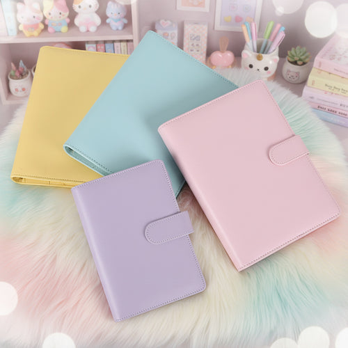 Four colorful planners (yellow, blue, purple, pink) on a fuzzy surface with pastel kawaii aesthetic background.