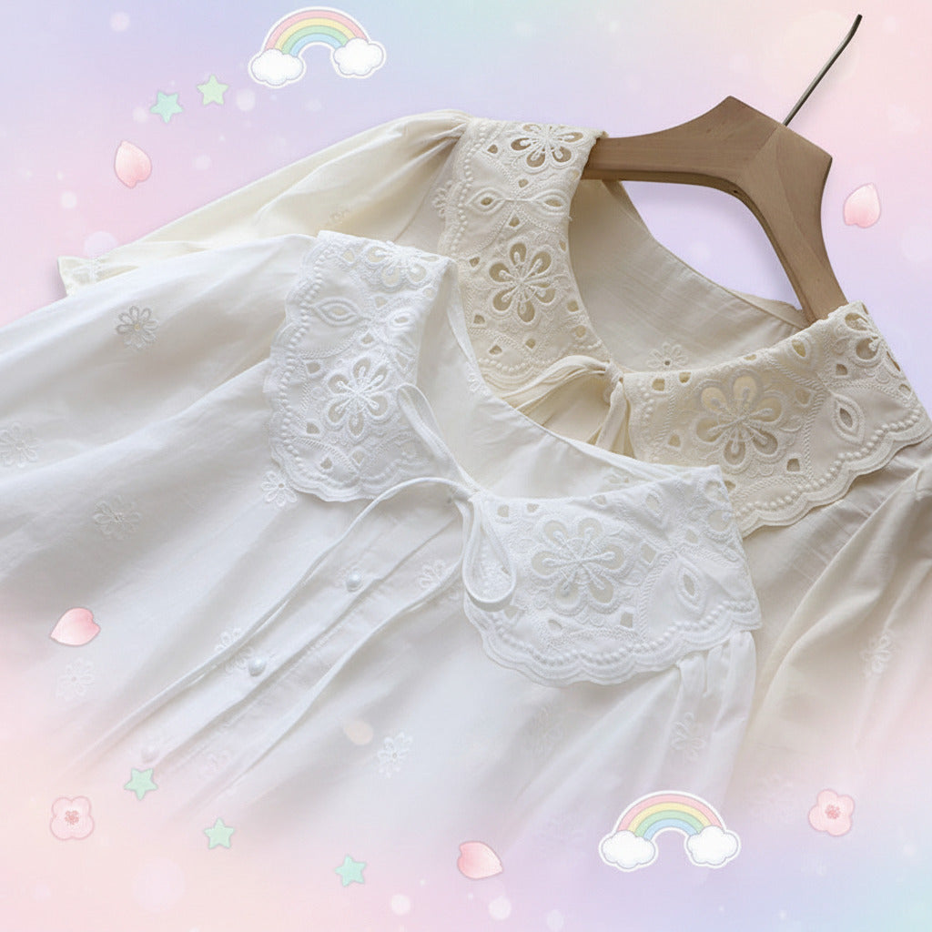 White blouse with lace details on a hanger against a textured white background