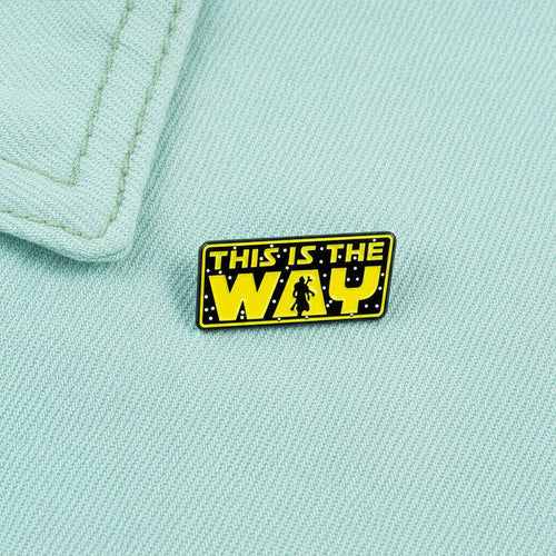 Enamel pin with 'This is the Way' text on pastel cyab colored denim fabric