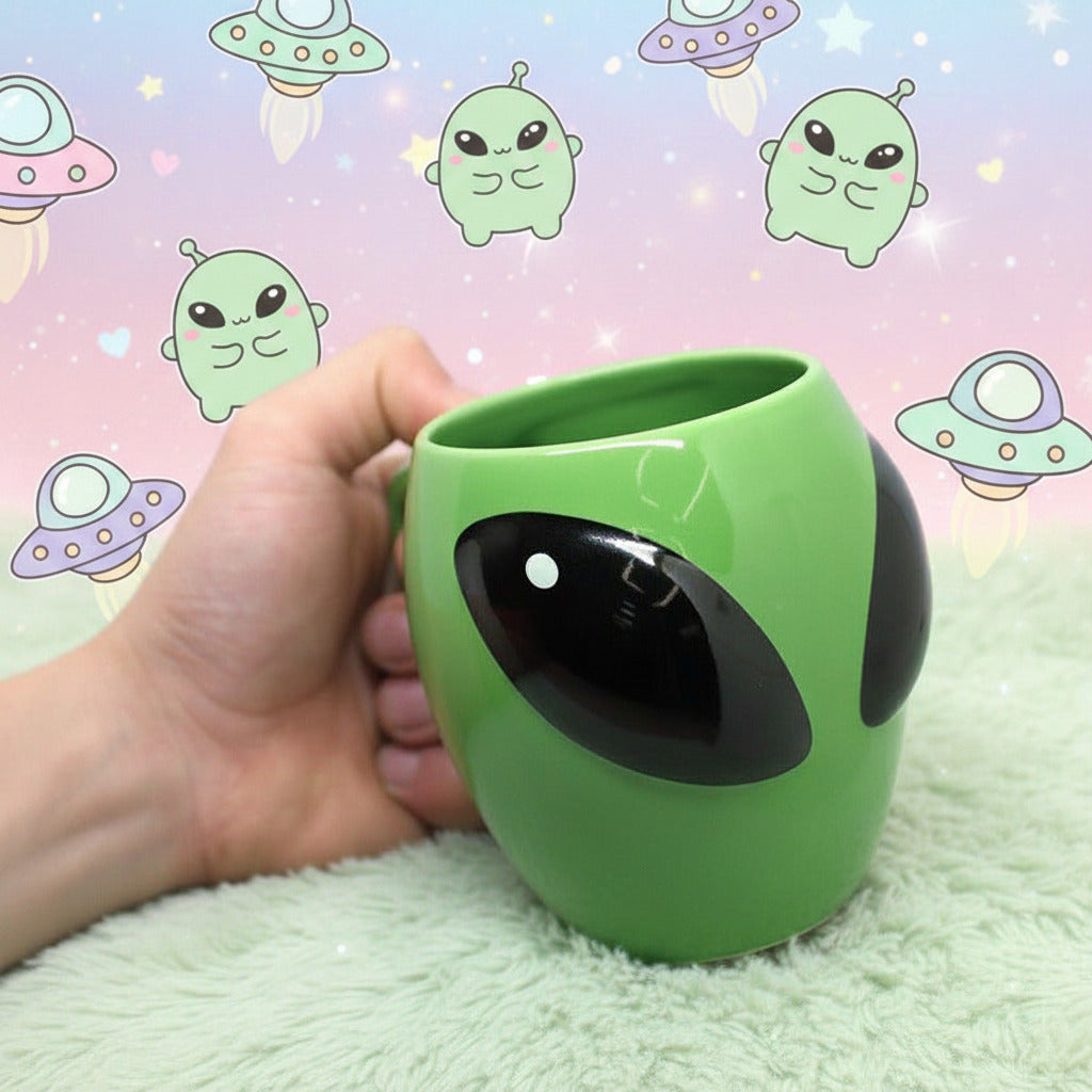 Green alien-shaped cup held by a hand on a white background.