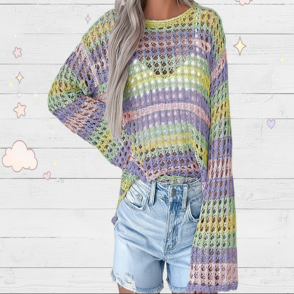 A person wearing a loose, long-sleeve crochet knit top with horizontal pastel stripes in purple, pink, yellow, green, and blue, paired with light-wash denim jeans.