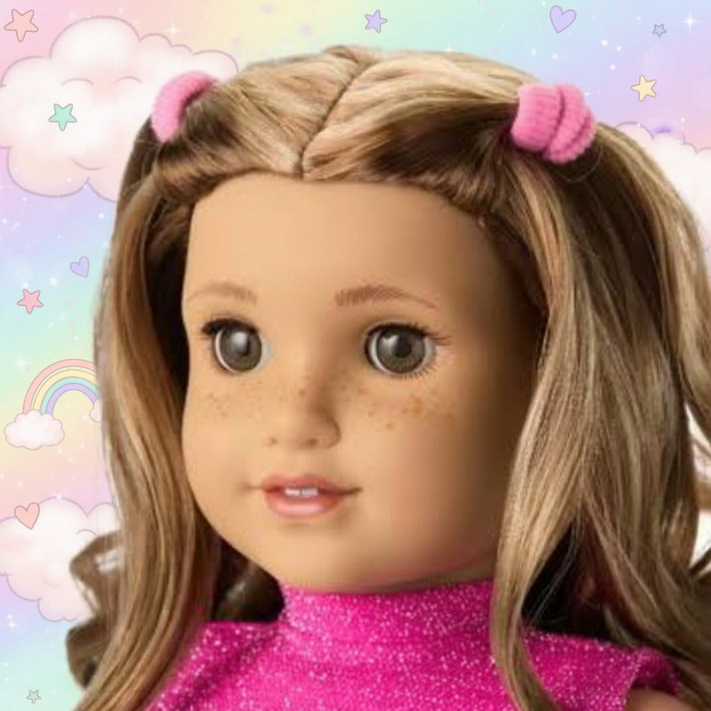 A close-up of an American Girl doll with light brown hair in pigtails, wearing a pink glittery top and pink hair bows, set against a plain white background.