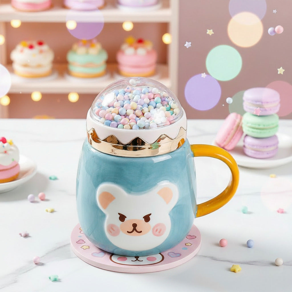 A light blue ceramic mug with a yellow handle and a cartoon bear face, topped with a clear dome filled with pastel gumballs and a gold rim, sitting on a white tabletop.