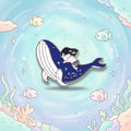 A mermaid riding a whale enamel pin on a plain white background.