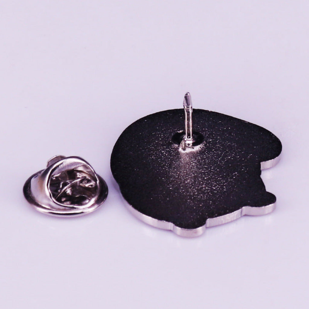 Black glittery pin with a metallic clasp on a light purple background