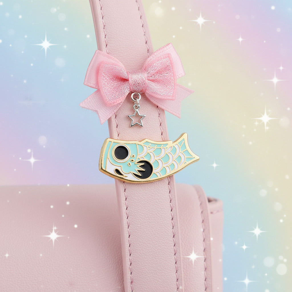 Fish-shaped enamel pin with a black circle and white patterns on a light blue background