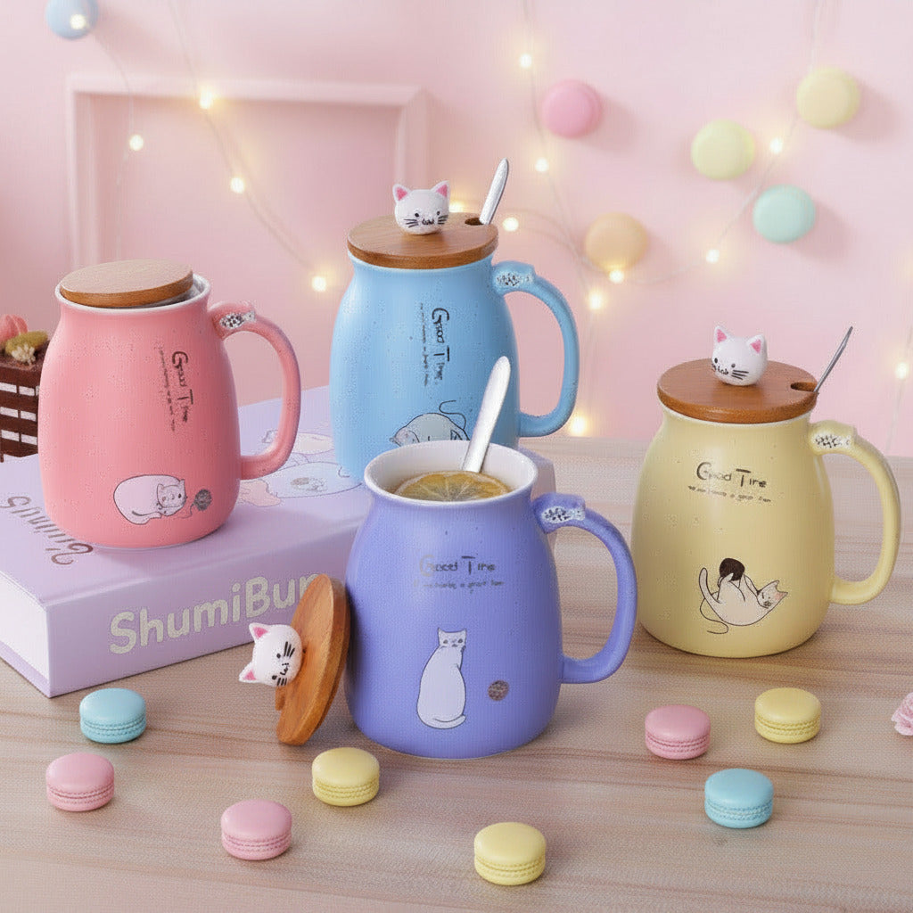 Four ceramic mugs with wooden lids and small cat figurines on top, arranged on a tabletop. The mugs are pink, blue, purple, and yellow, each with a spoon inside and printed cat illustrations and the words 'Good Time.