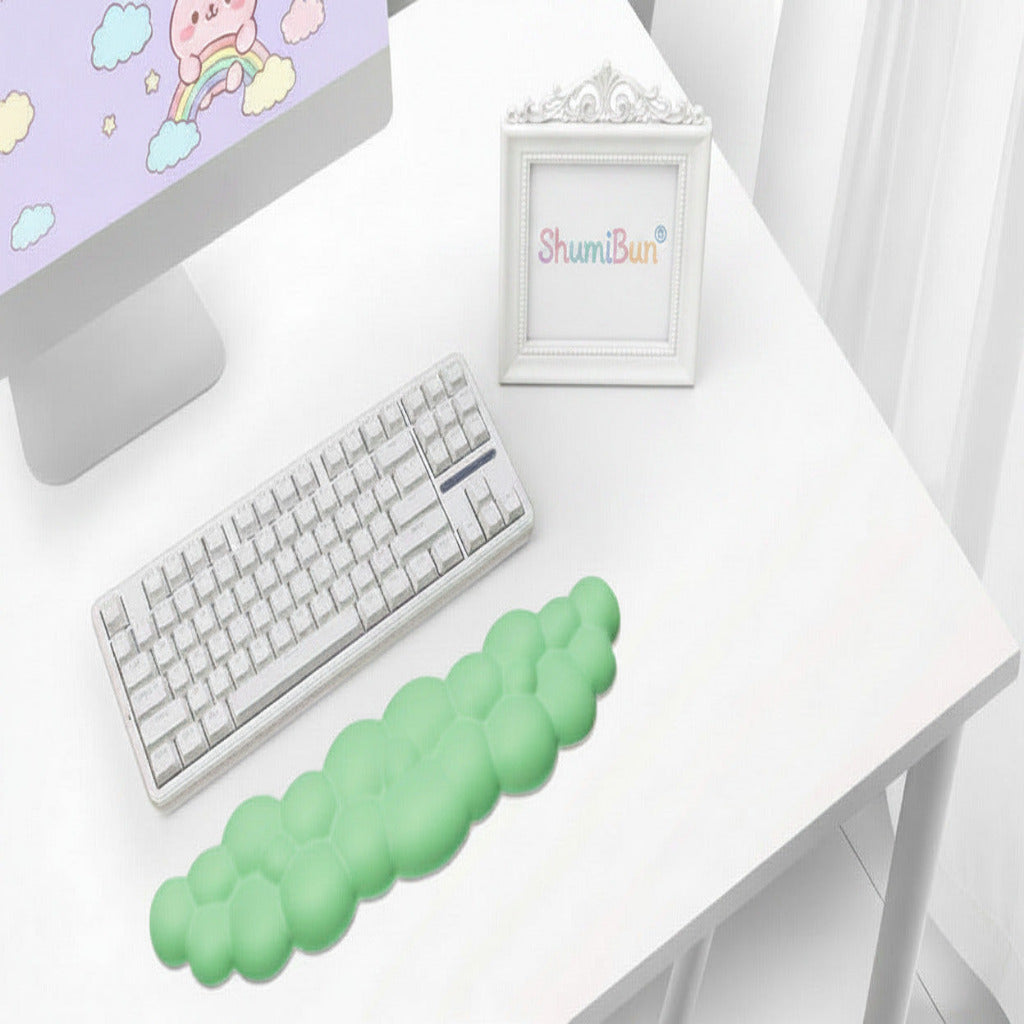 Green cloud-shaped desk pad on a white desk with keyboard and mouse.