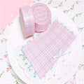 Pink and white checkered fabric with a roll on a floral patterned background