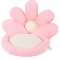 A pink flower-shaped plush cushion with cream-colored center and seat, photographed on a plain white background.