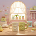 Two ceramic mugs with loop handles sit on a light wood surface. The front mug is cream-colored with a raised heart design, and the rear mug is light yellow-green with a raised circular design.