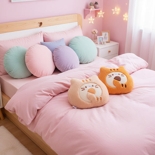 Two cute animal-shaped cushions on a surface with a book and mug in the background.