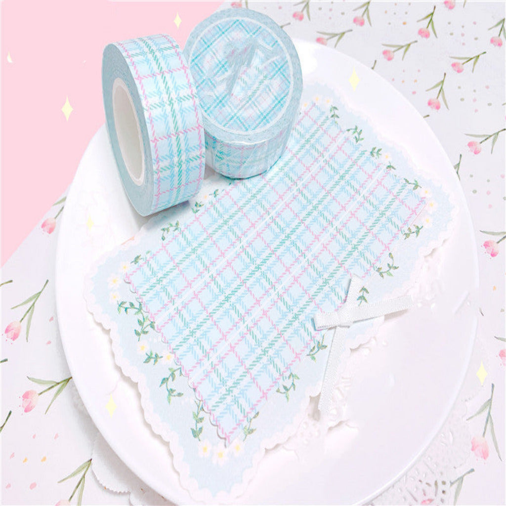 Two rolls of blue and white checkered tape on a white plate with a floral background