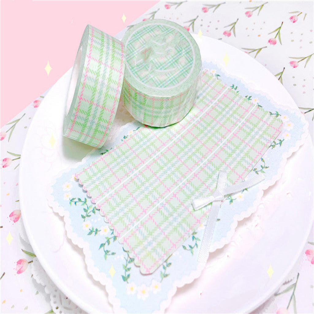 Two rolls of green and white checkered tape on a white plate with a floral patterned background.