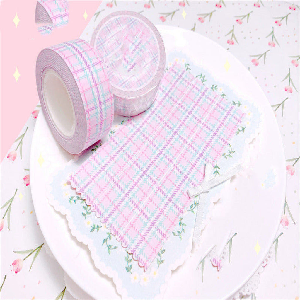 Two rolls of pink and white plaid tape on a floral-patterned surface