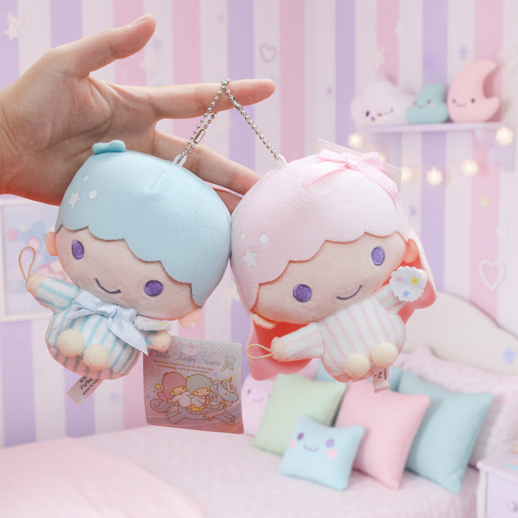 Two small plush character keychains held in a hand against a white background. One plush has light blue hair and matching outfit, and the other has pink hair and matching outfit.