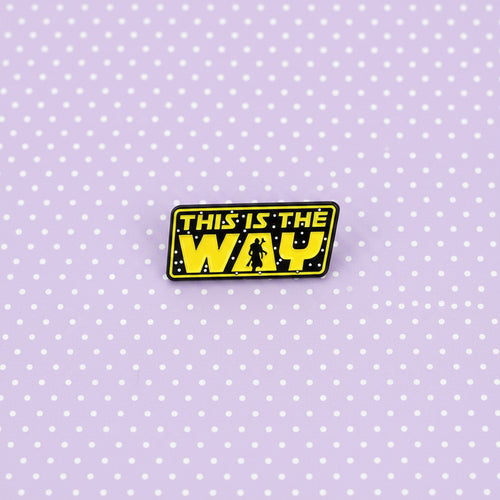 A rectangular enamel pin featuring the iconic yellow and black Star Wars logo text that reads 'THIS IS THE WAY' with a small silhouette of a stormtrooper, shown on a light lavender background.
