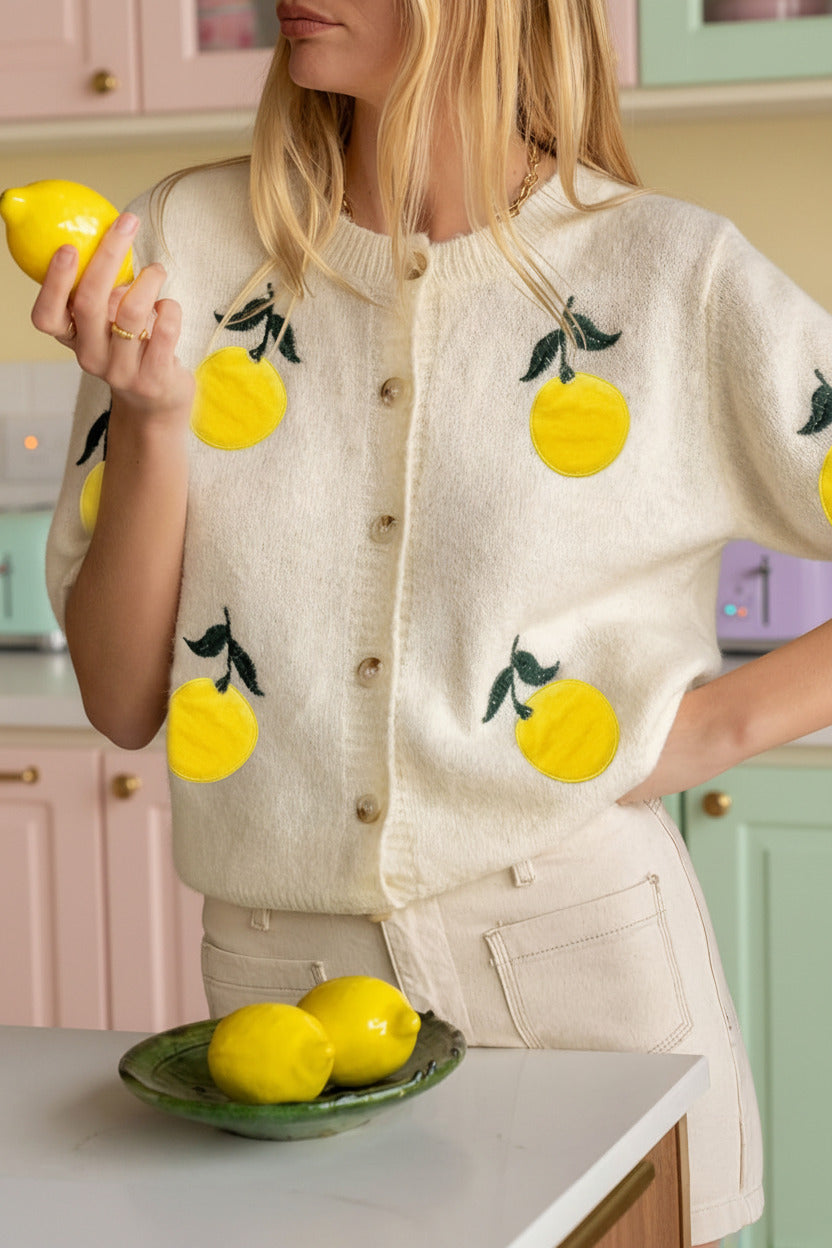 Person wearing a sweater with lemon designs in a kitchen setting