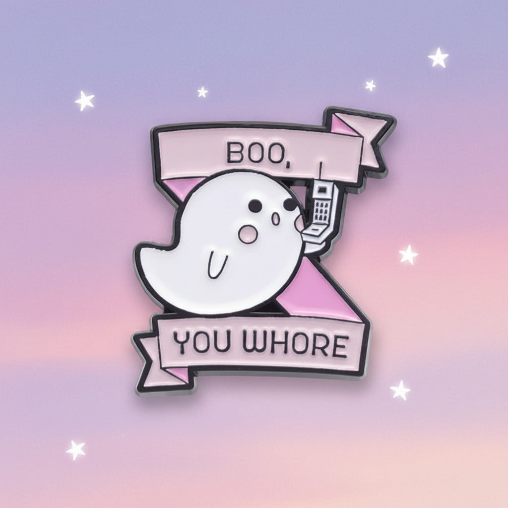 A cartoon ghost enamel pin with pink banners reading 'BOO.' and 'YOU WHORE' on a plain white background.